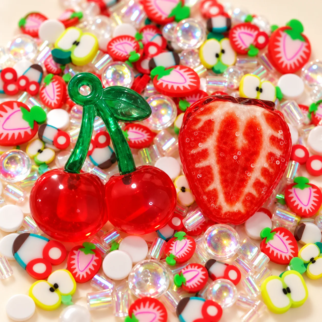 Close-up of large resin cherry and cut-strawberry charms with small polymer clay fruit slices