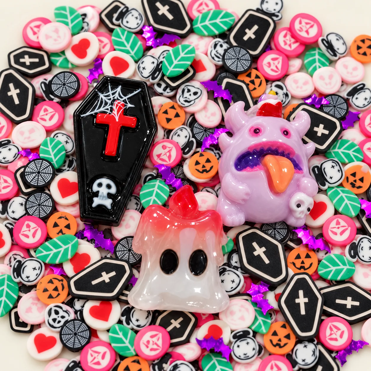 Close-up of resin coffin, lavender monster and ghost focal charms among Halloween slices