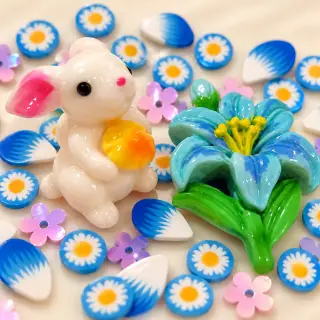 Close-up of white rabbit and glossy blue flower focal charms with daisy slices