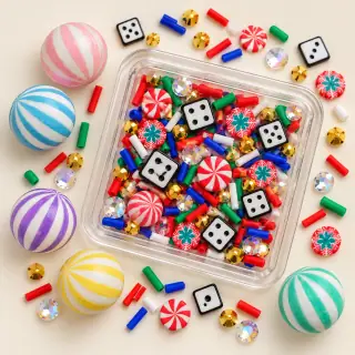 Illustrative dry shaker with small candy and dice fillers, and large striped charms beside it