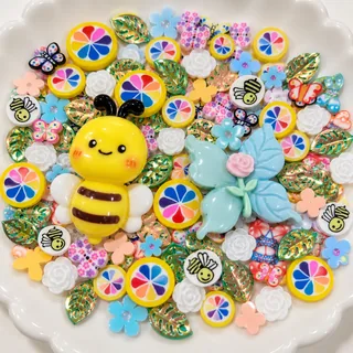 Close view of yellow bee and pale blue flower-like focal charms with rainbow and floral filler pieces