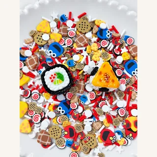Close view of round white-topped and yellow triangular charms surrounded by snack-patterned filler pieces