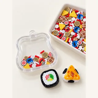 Illustrative dry shaker with selected small snack motifs and large focal charms loose beside it