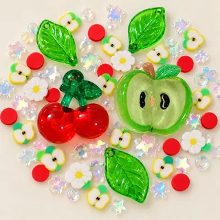 Close view of red cherry and pale green half-apple charms with transparent leaves and daisy filler pieces