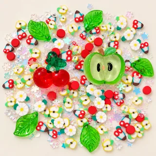Studio overview of cherry and green apple resin charms with daisies, green leaves and small fruit pieces