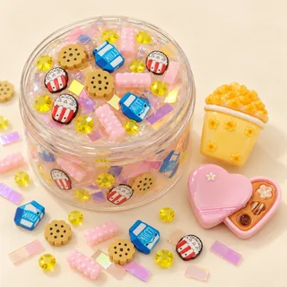 Illustrative slime jar with selected small popcorn, milk and cookie pieces and large resin charms outside