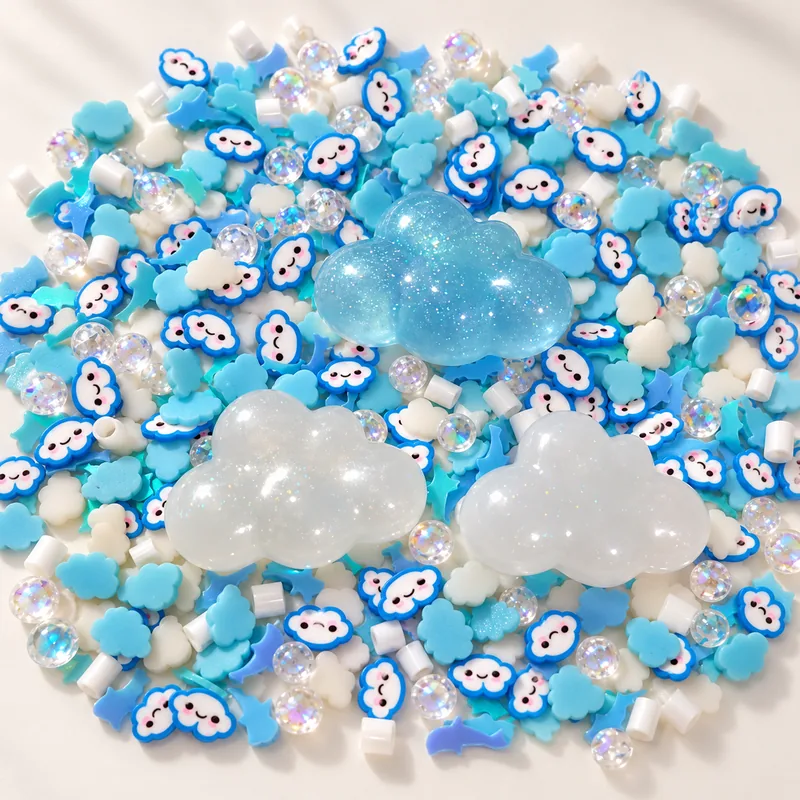 Studio overview of three large blue and white cloud charms with smiling blue-outlined cloud slices and clear beads