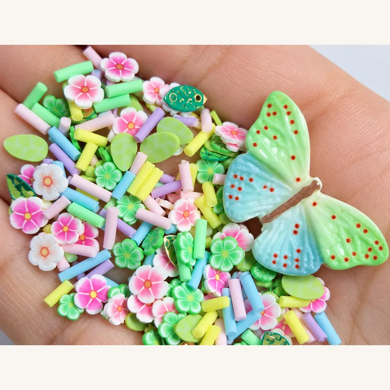 Studio overview of one pastel green-blue butterfly with pink-white flower slices, green accents and pastel rods