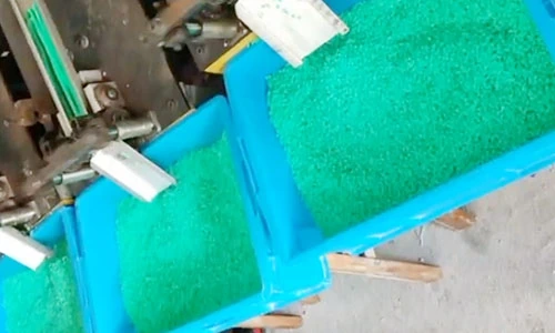 Green decorative slices collected in blue bins beneath cutting equipment