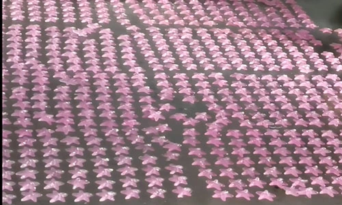 Rows of pink resin decorative shapes laid out on a production tray