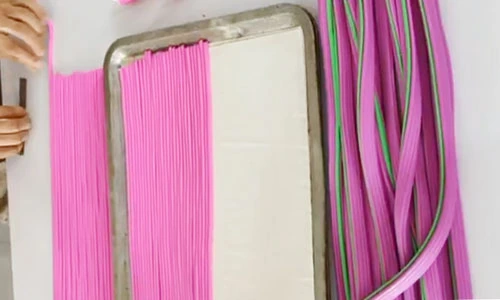 Pink clay canes aligned in a frame beside longer pink and green strands