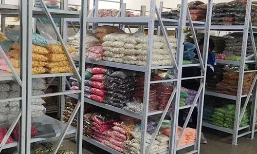 Warehouse shelving with bags of decorative components separated by colour and style