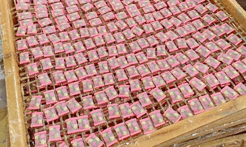Pink rectangular decorative charms arranged on a mesh finishing rack