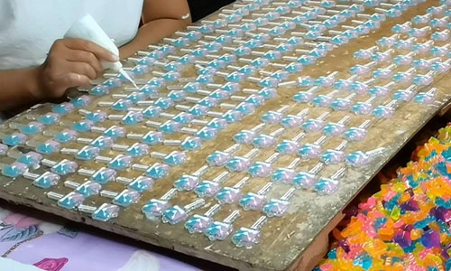 Worker applying a surface finish to decorative pieces arranged on a board