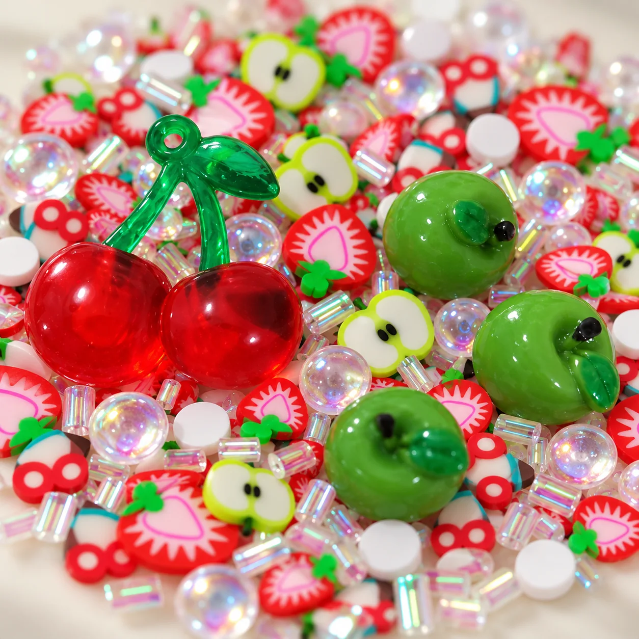 Close view of red resin cherry and green apple charms with strawberry and apple slices