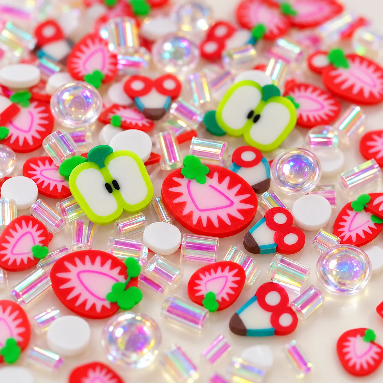 Close view of red strawberry slices, lime-edged apple slices and transparent decorative beads